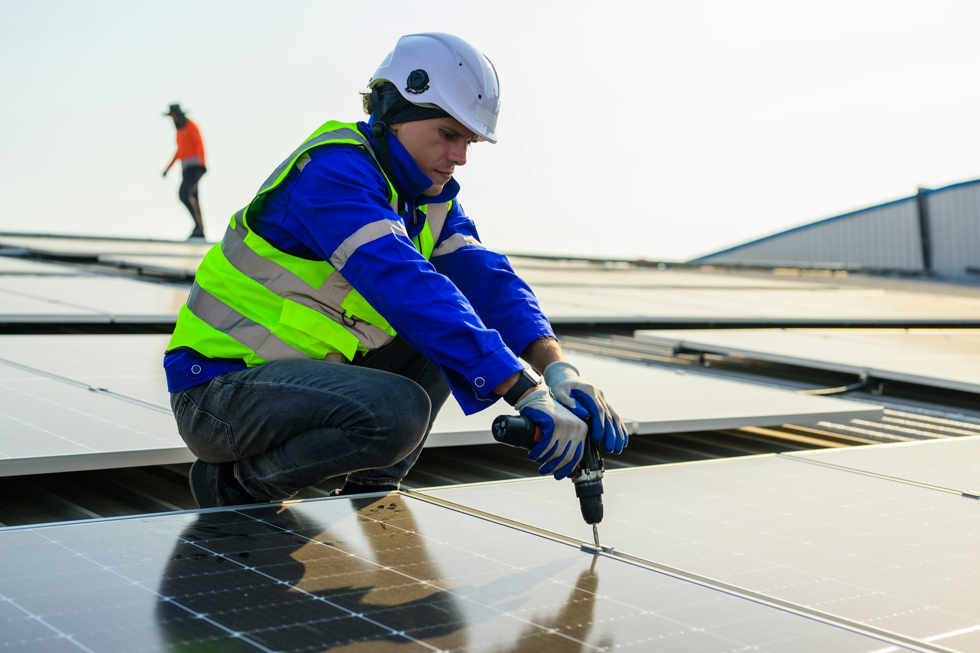 Professional technicians installing solar panels on rooftop of plant