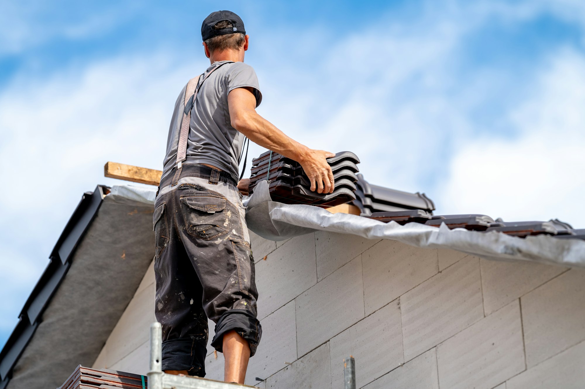 roofer on the roof of a family house, building a roof covering from ceramic tiles